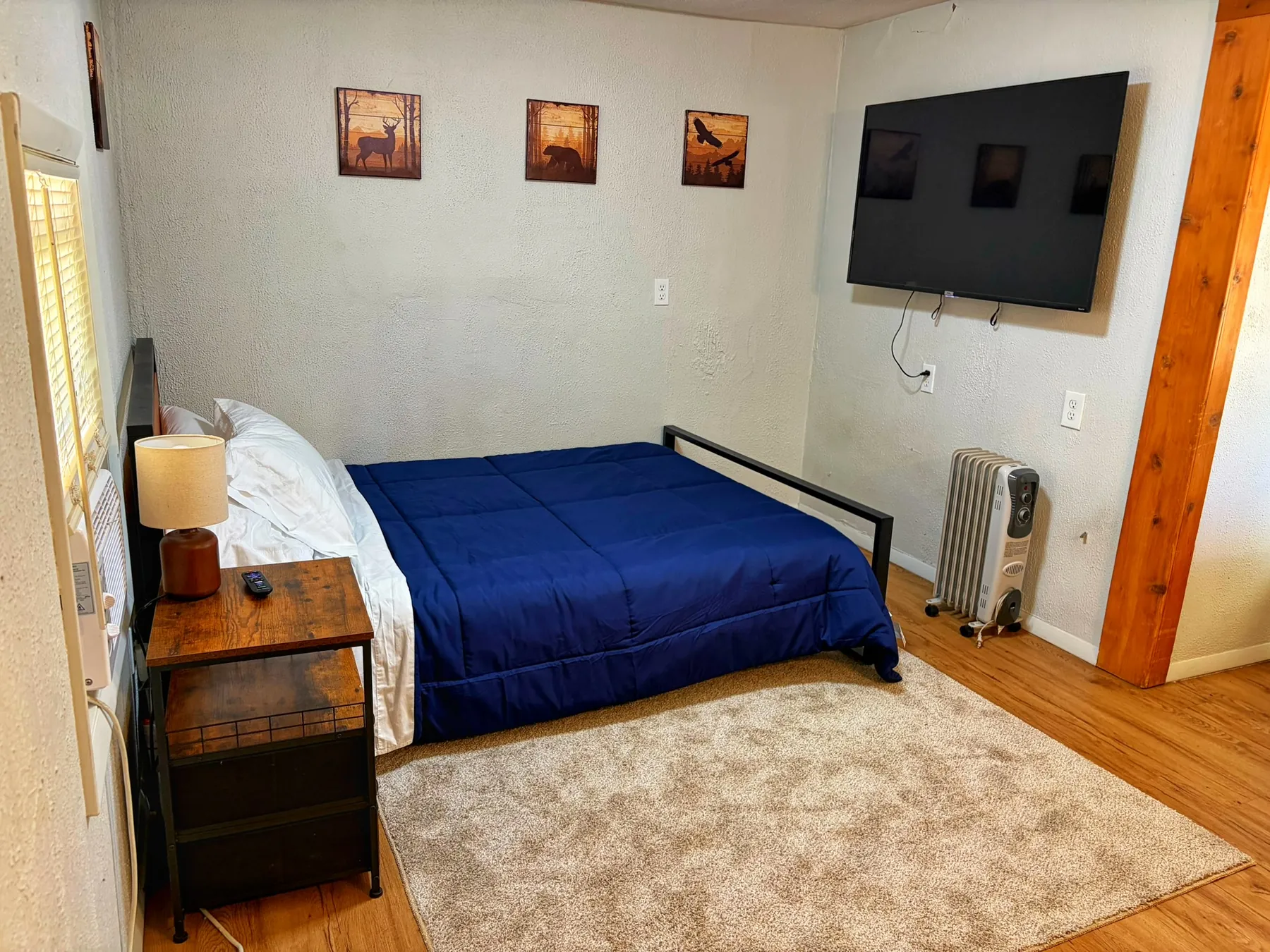 Motel bedroom with a blue-covered queen bed and seating